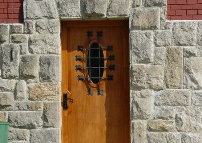 Fa bejárati ajtó, ovális ablakkal, kovácsolt vas díszítéssel